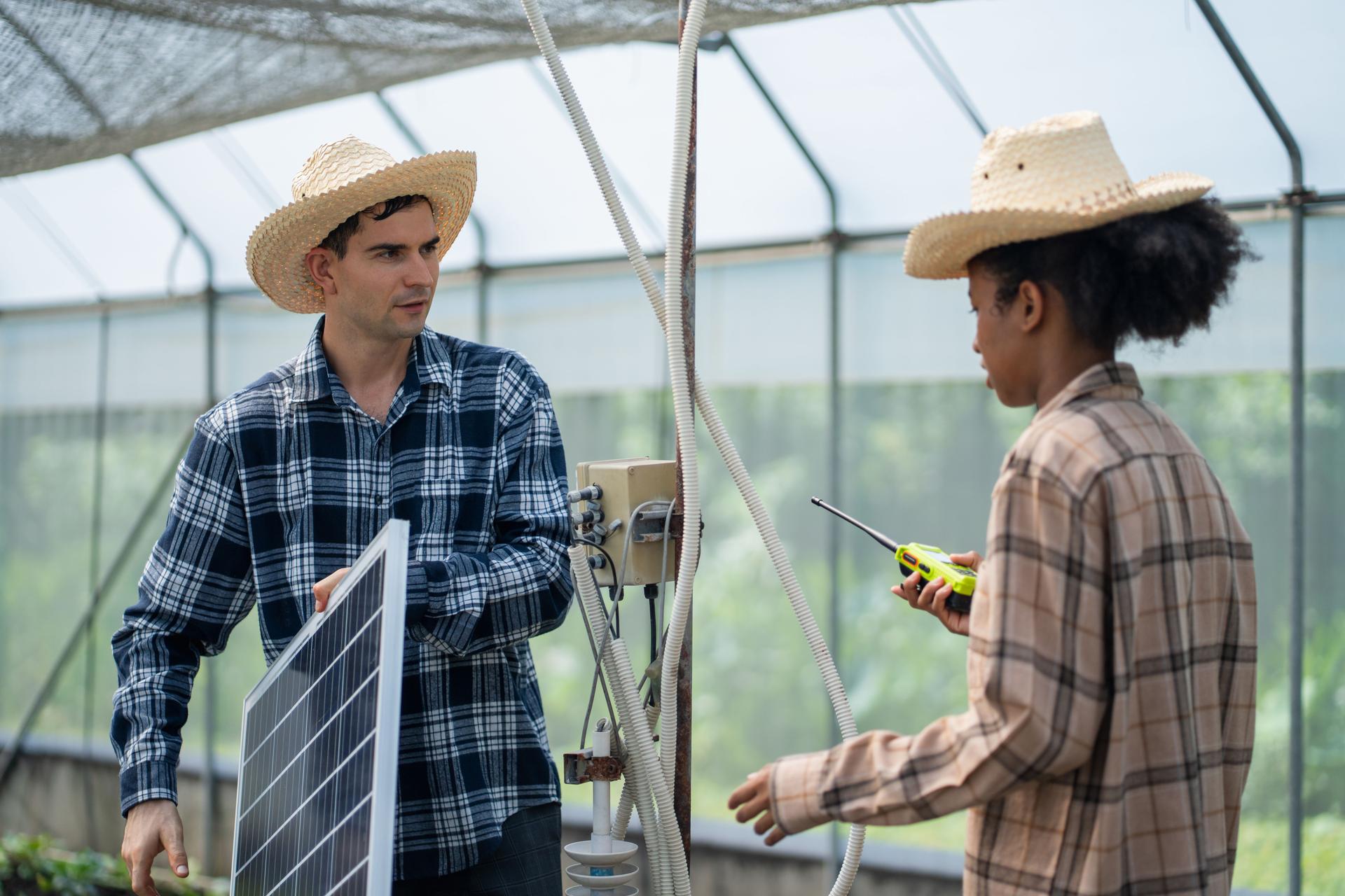 Farmers planning to install solar panels on their farm to power greenhouses for crop production, renewable energy and agriculture concept.